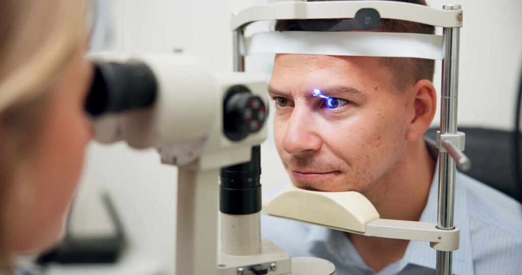 man behind slit lamp examination